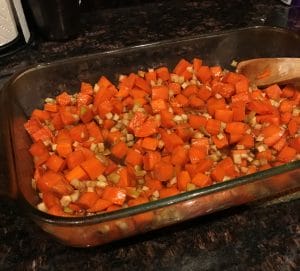 Completed view of the chopped sweet potatoes and apples dish.mixed together in a clear glass pan.
