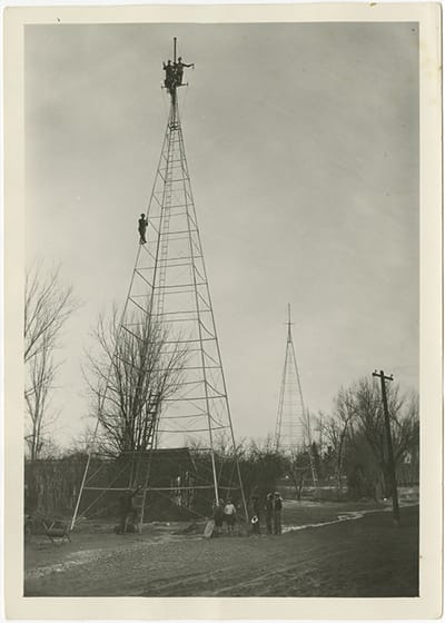 Radio tower with two individuals at top and another holding on midway up