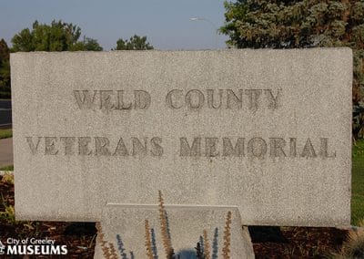 Image of a grey stone marker with the words "Weld County Veterans Memorial" inscribed on it.