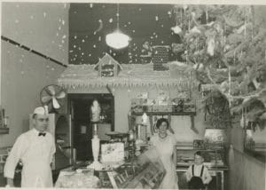Interior view of a shop with a display cabinet in the foreground. Shop is decorated in a winter scene. 