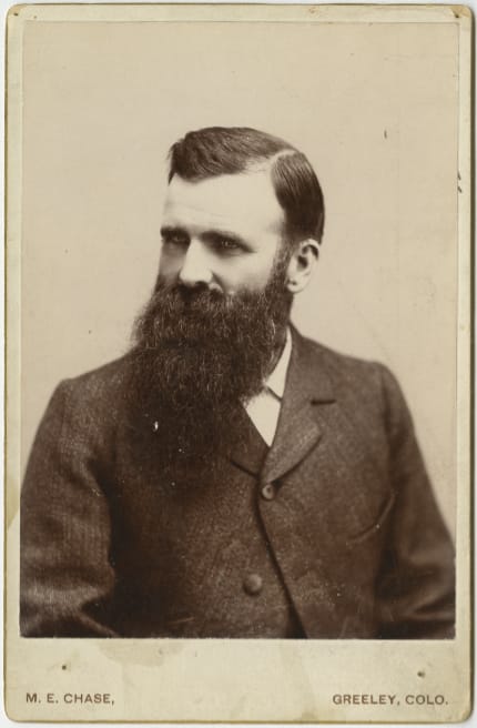Portrait of Dr. Jesse Hawes wearing a dark dress coat and with a full beard.